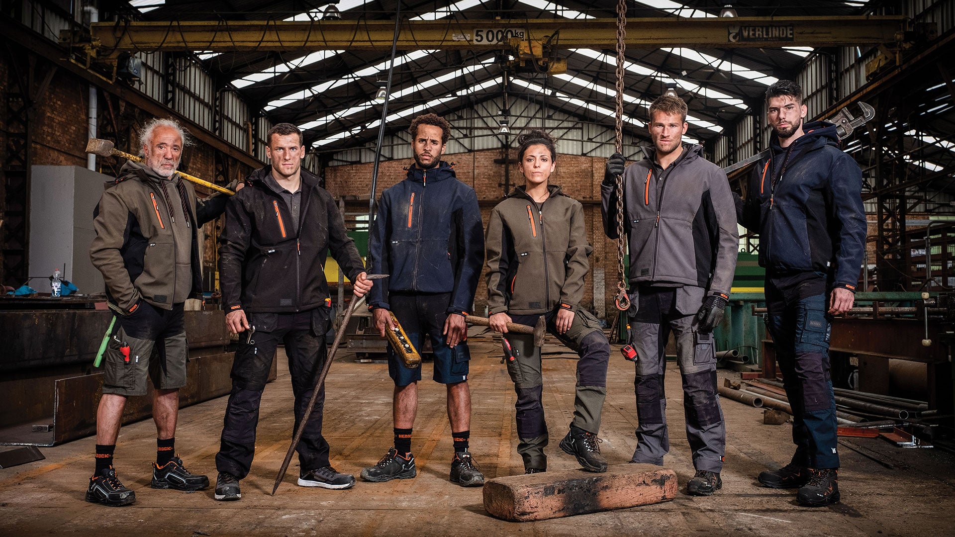 Six workers wearing rugged outdoor workwear standing in a warehouse.