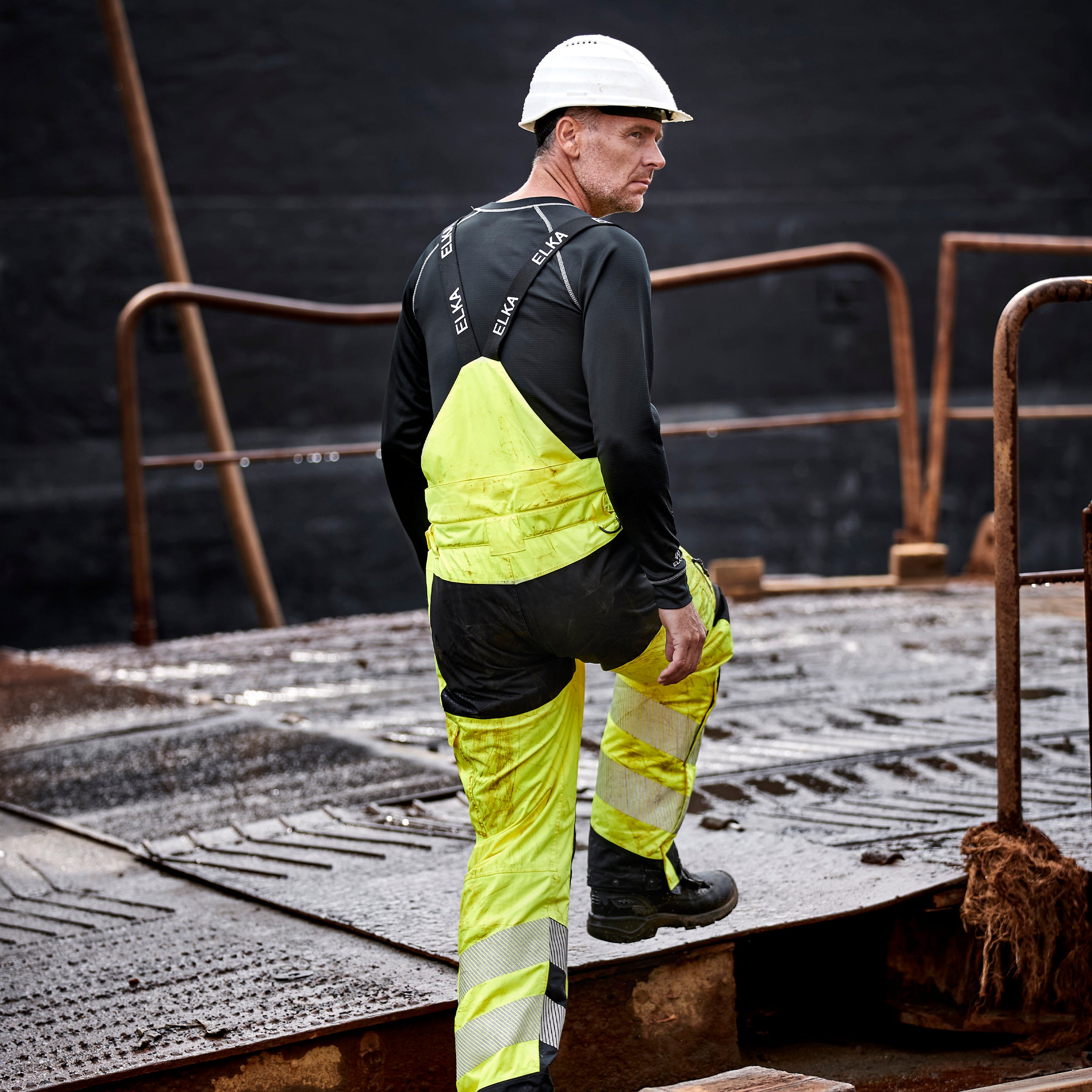 worker wearing yellow elka hivis waterproof trousers with braces